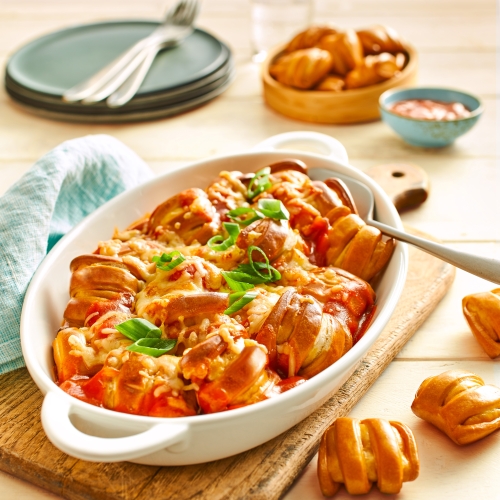 Baking dish with Pretzel Bites in tomato sauce, baked with cheese and spring onions.