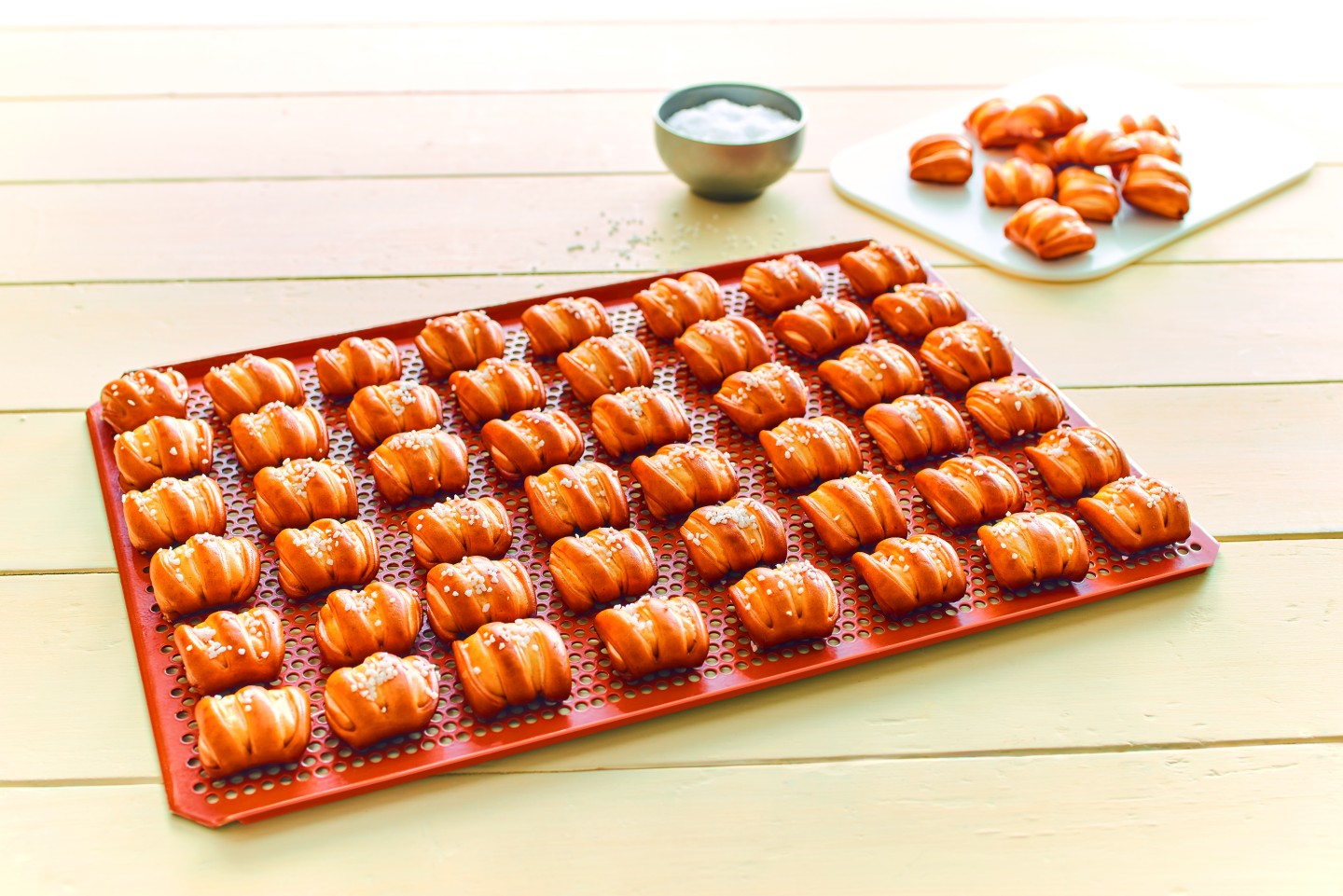 Draufsicht auf rotes Backblech mit frisch gebackenen goldbraunen Ditsch Pretzel Bites.