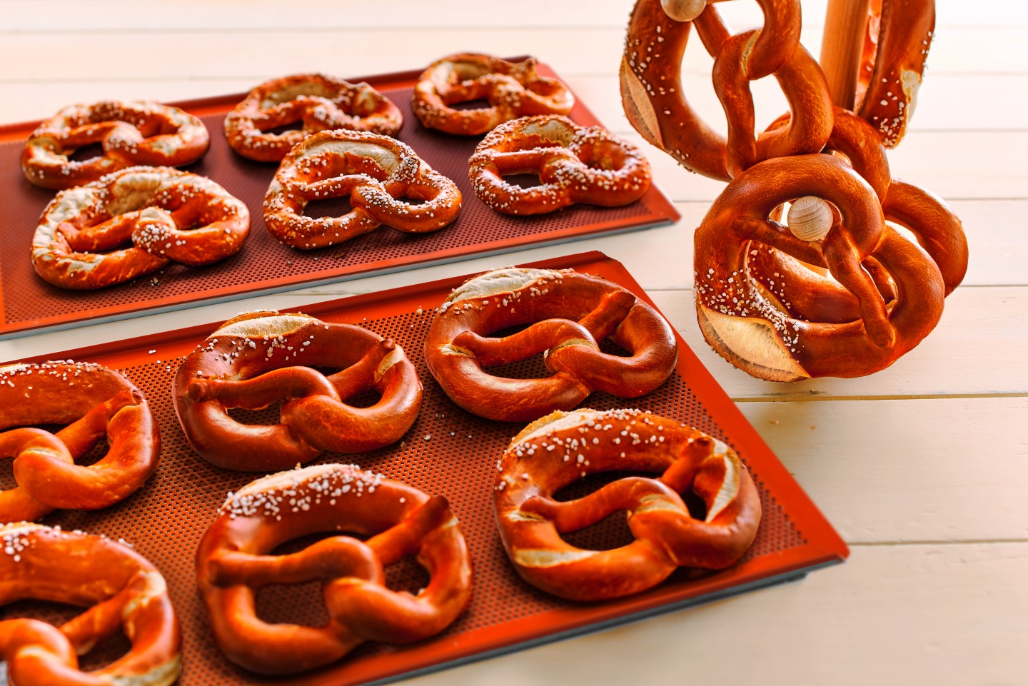 Two baking sheets with freshly baked Ditsch pretzels, pretzel decoration in background.
