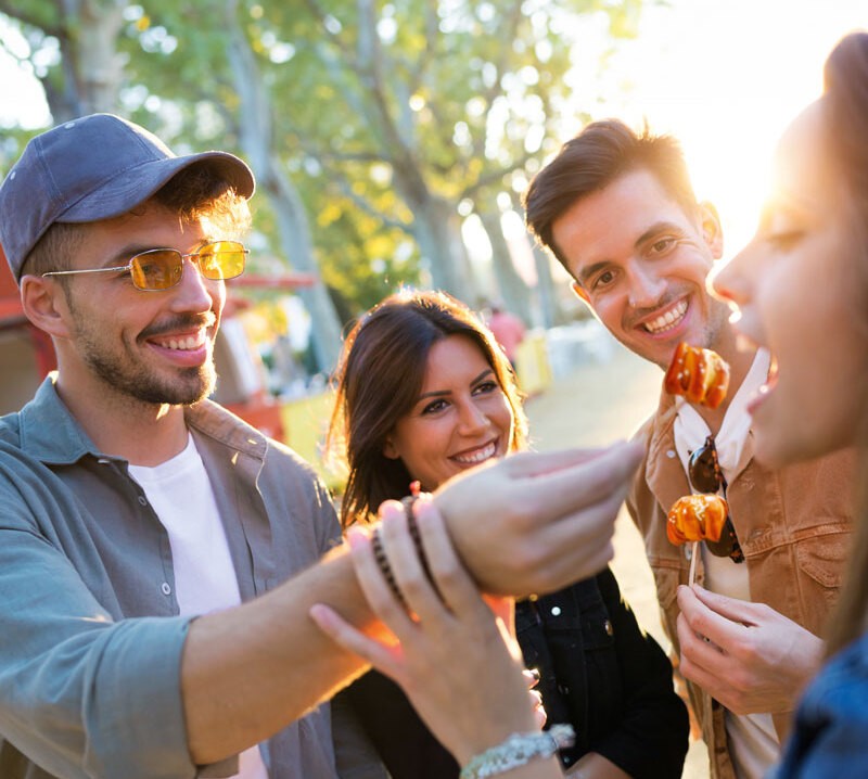 Four young people sharing Ditsch Pretzel Bites outdoors - a scene of togetherness.