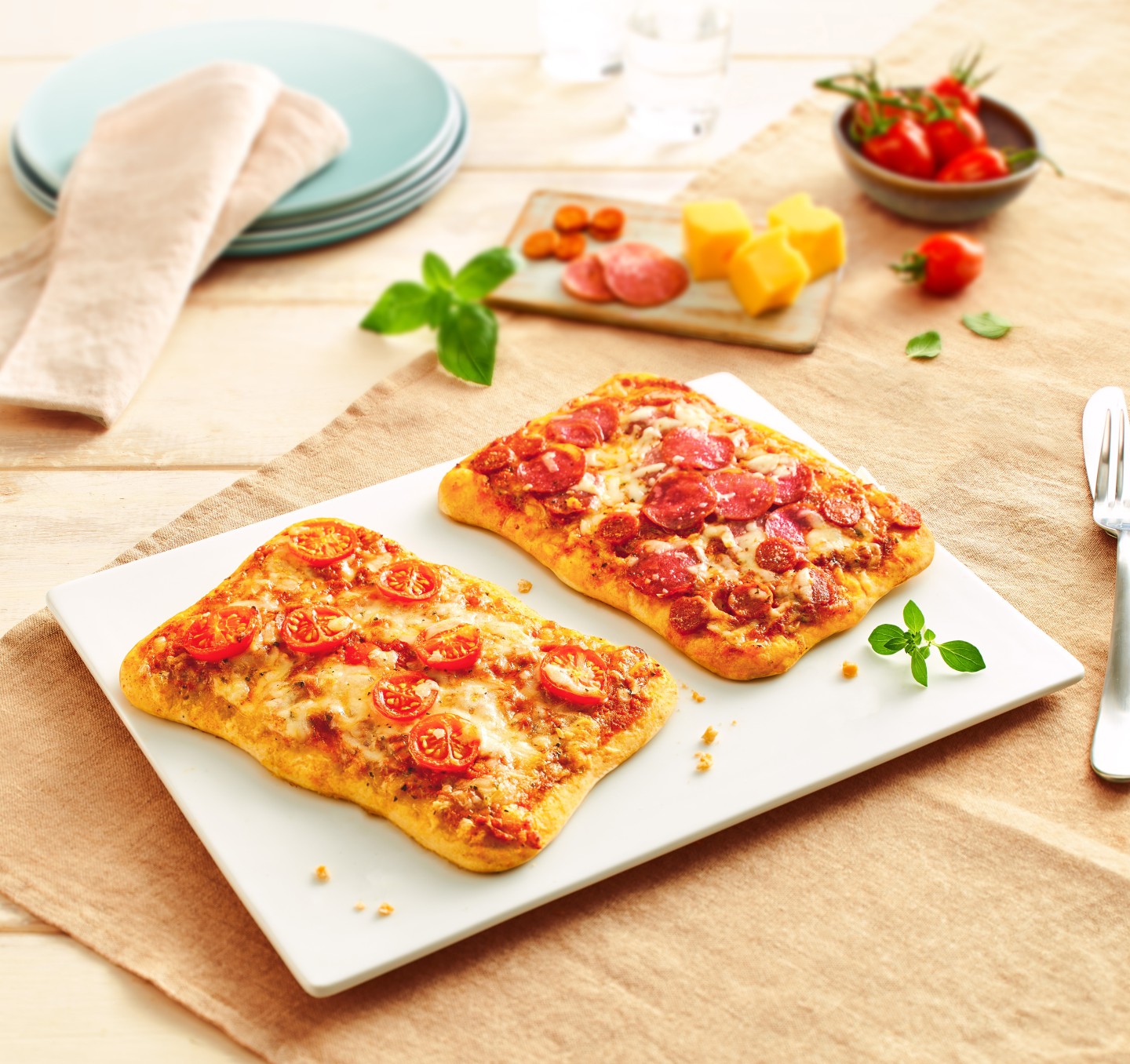 Zwei rechteckige Ditsch Premium-Pizzen mit Tomaten und Mozzarella auf einem weissen Teller.