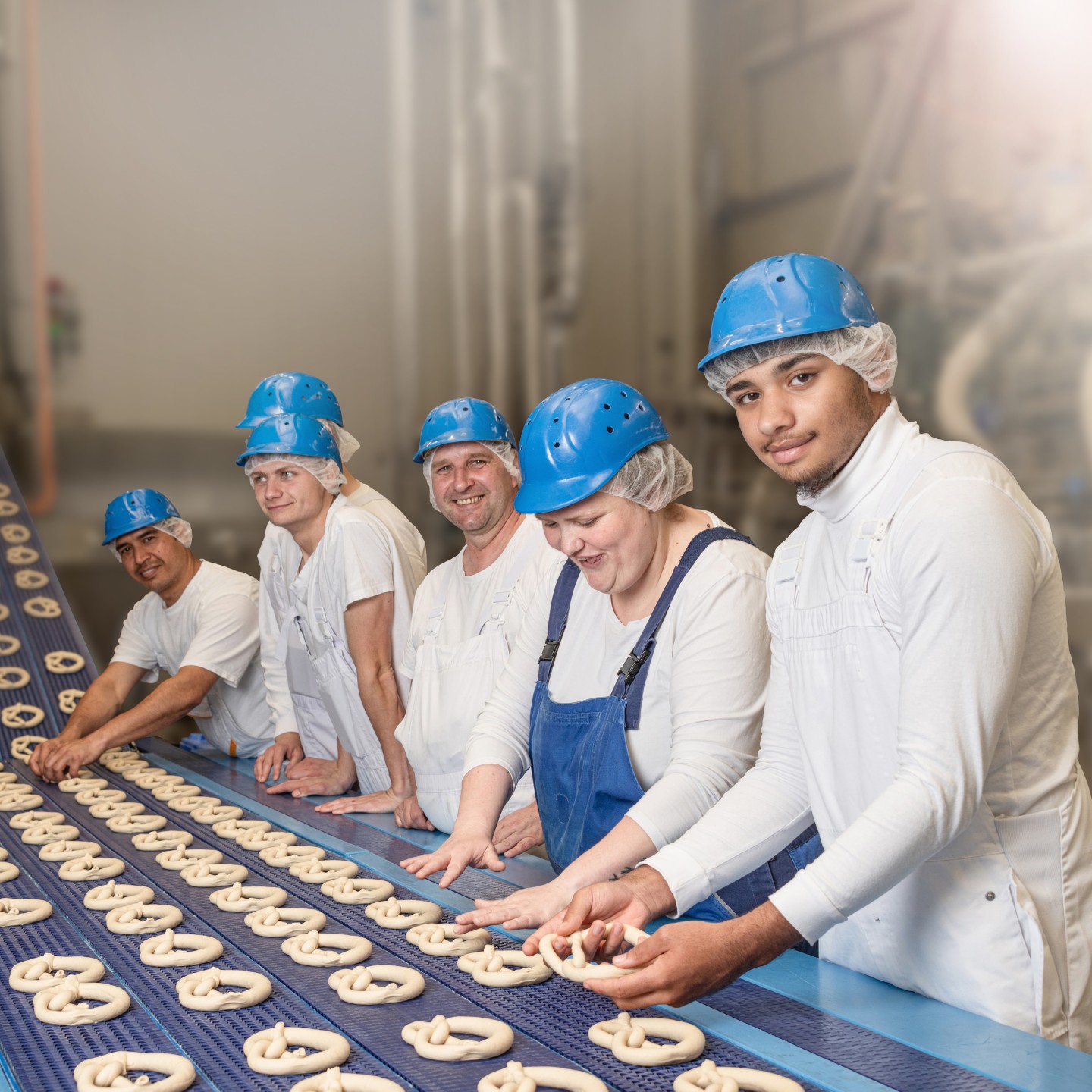 Ditsch-Mitarbeiter in Schutzkleidung und blauen Helmen an der Produktionslinie.