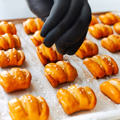 Pretzel bites on a baking sheet; salt is sprinkled over them.