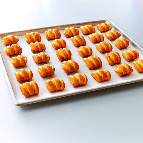 Backblech mit ca. 30 frisch gebackenen, goldbraunen Ditsch Pretzel Bites in Reihen.