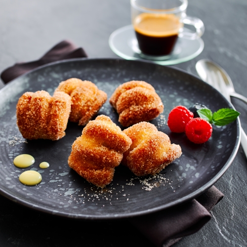 Black plate with sugar-dusted Dessert Bites, raspberries and mint.
